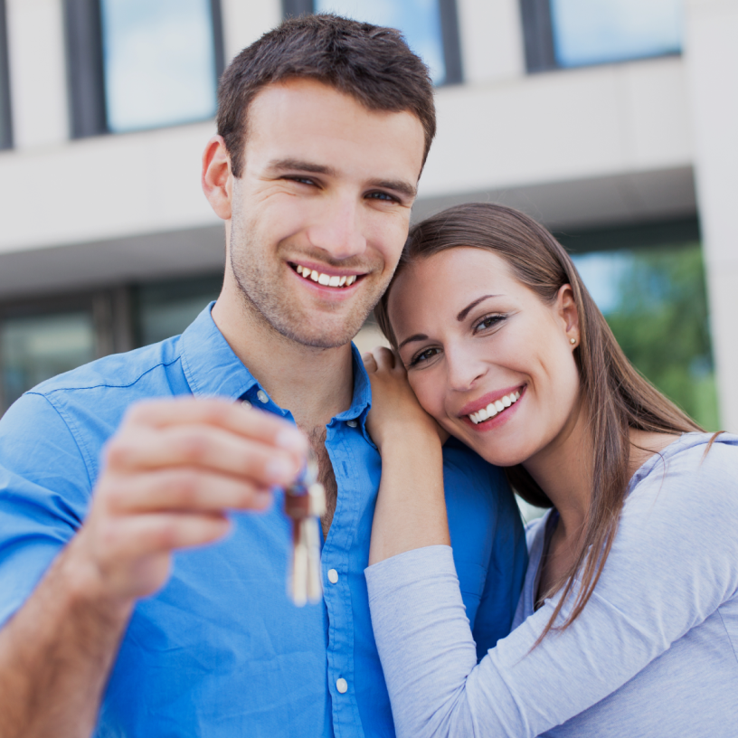 Excited couple holding a house key, celebrating their new home purchase