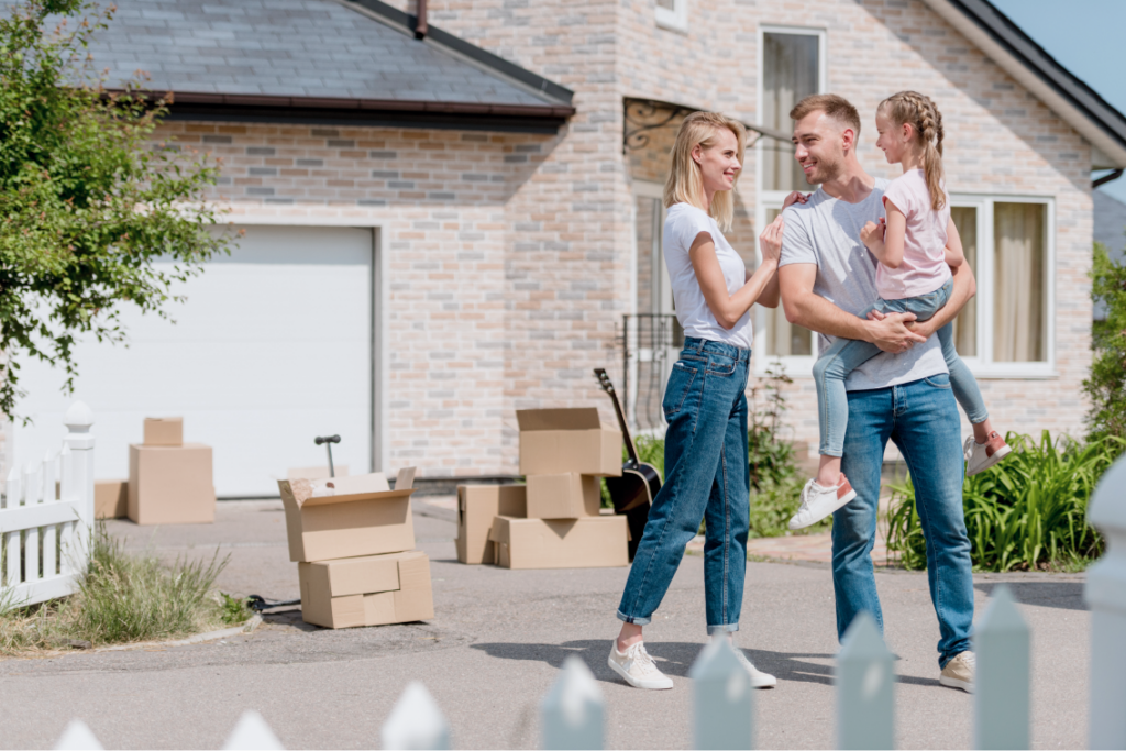 Happy family standing together in front of their home, smiling warmly